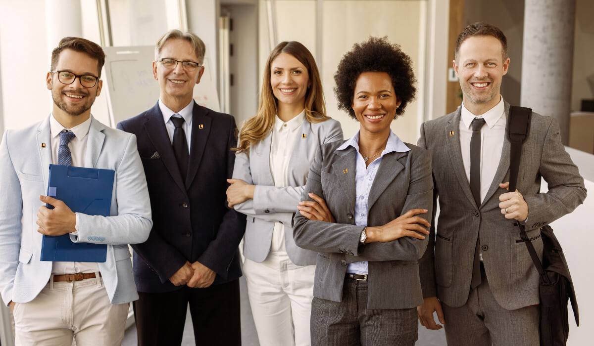 Group of professionals standing together in an office smiling 