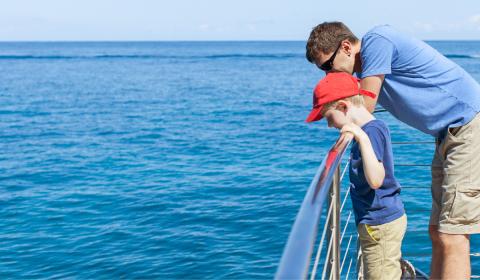 Father on son on edge of boat looking down