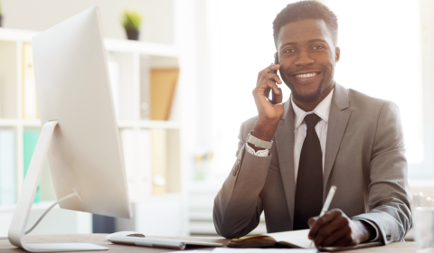 Man in suit speaking on phone next to computer