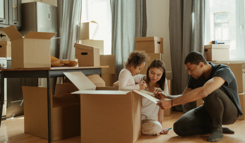 Young couple sitting on floor of new home surrounded by moving boxes