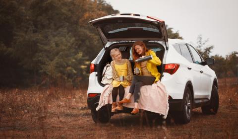 Mother and daughter having picnic in SUV trunk