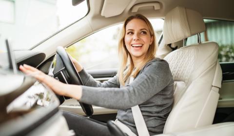Female student driver behind the wheel of a car smiling