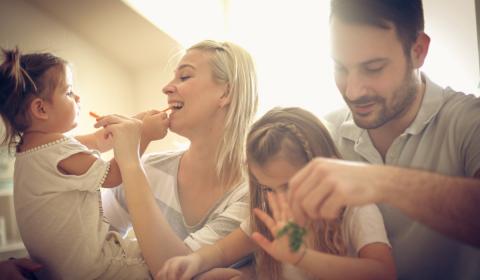 Family of 4 young children laughing at home