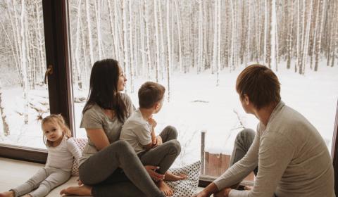 family looking outside window in home winter