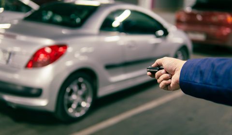 Main tendant une télécommande vers une automobile